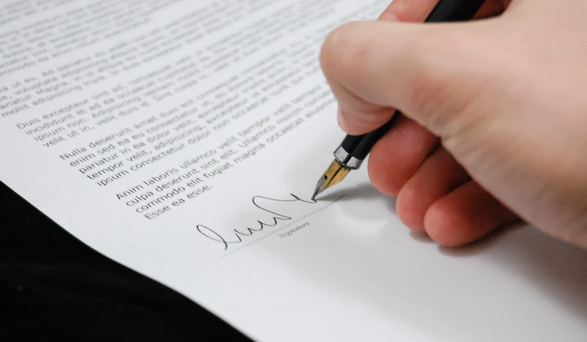Person underskriver dokument til oprettelse af aktiesparekonto.